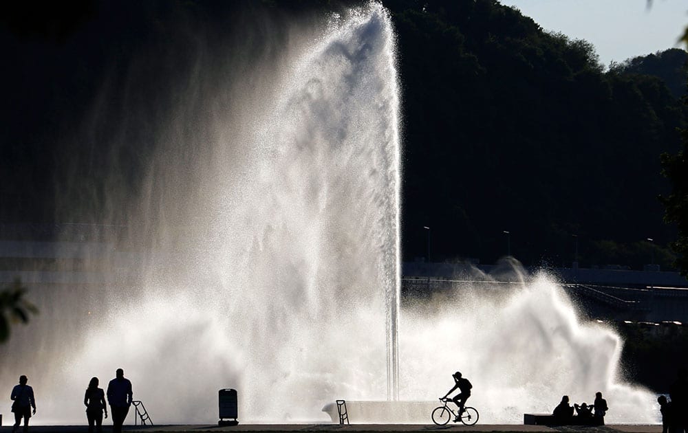 Visitors to Point State Park are silhouetted against a fountain at the confluence of the Monongahela, Allegheny, and Ohio rivers in downtown Pittsburgh.