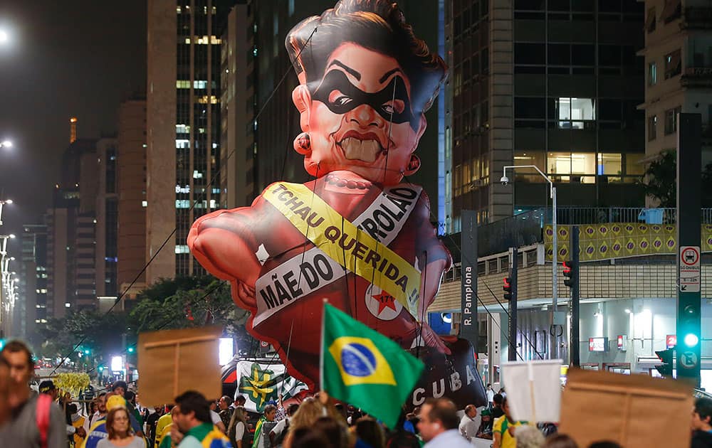 People protest next to large inflatable doll of Brazil's President Dilma Rousseff wearing a presidential sash with the words 