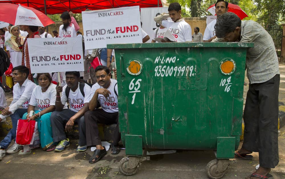 A poor man scavenges for plastic bottles in a dustbin as activists and people affected with HIV hold a rally to urge China, 
Germany and Japan to step up their contributions to the Global Fund to Fight AIDS, Tuberculosis and Malaria in New Delhi.