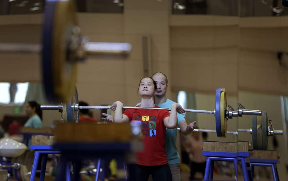 China's Deng Wei is helped by her coach as she attempts a lift during a weightlifting training for the Rio 2016 Olympic Games 
at the General Administration of Sport in Beijing.