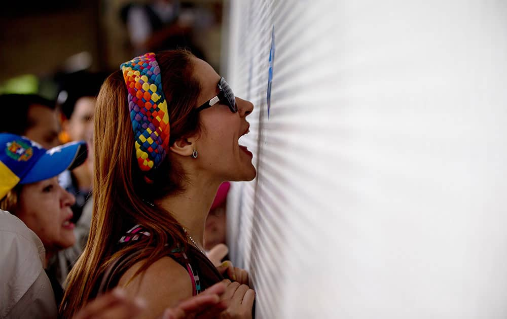 An anti-government demonstrator shouts insults at National Guard soldiers behind a fence that blocks demonstrators from reaching the National Electoral Council (CNE) in Caracas, Venezuela.