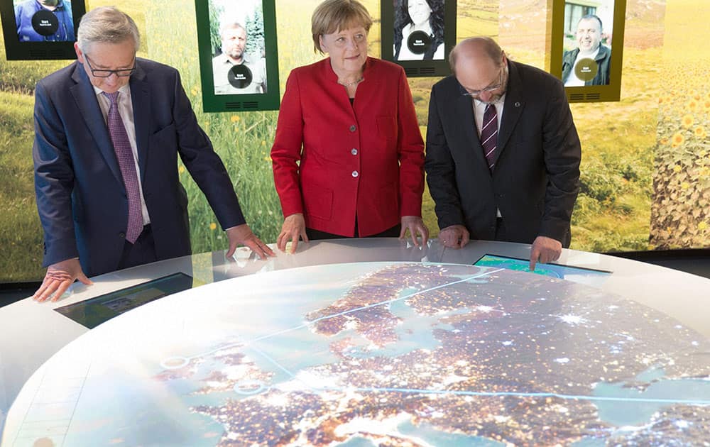 German chancellor Angela Merkel, center, European Parliament President Martin Schulz , right, and European Commission President Jean-Claude Juncker look at a map during the opening of an exhibition about Europe in Berlin.