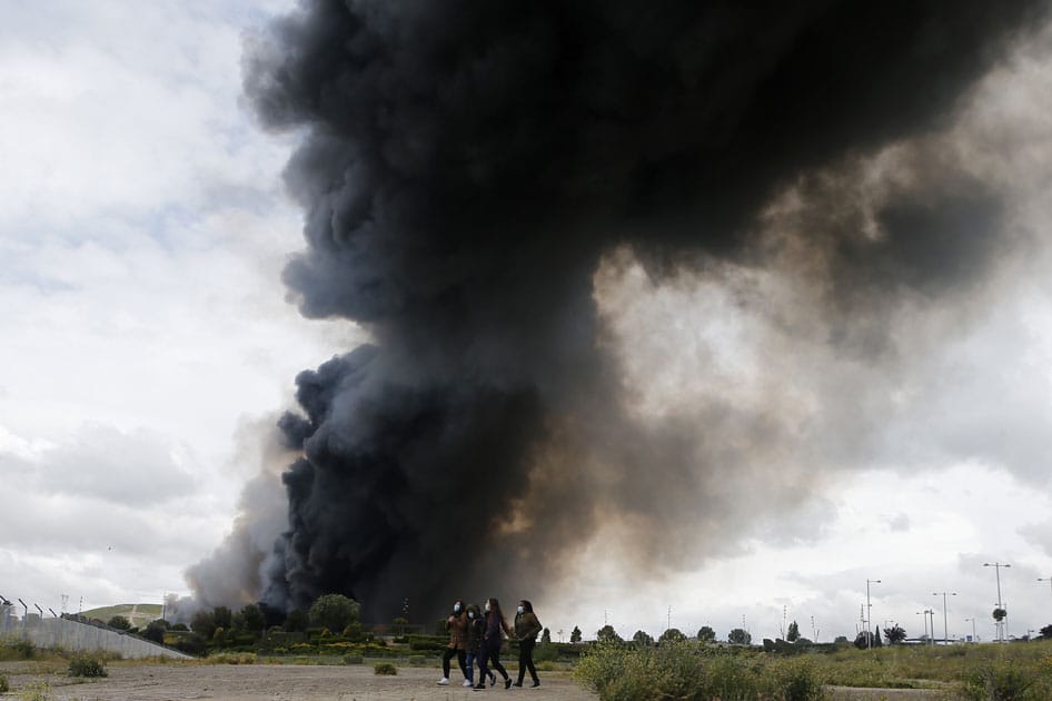 Four women walk with masks in front of billowing black smoke from a huge fire in Sesena, central Spain.A massive fire is raging at a sprawling tire dump in a town near Madrid, sending a spectacular cloud of thick black smoke into the air that's visible for at least 30 kilometers (20 miles).