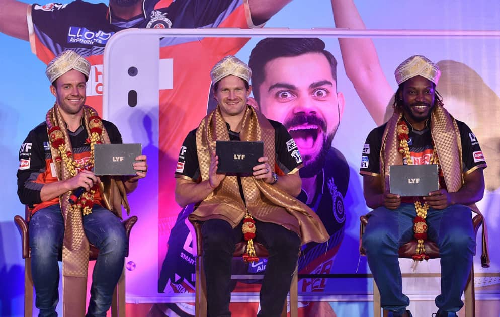 Cricketers AB De Villiers, Shane Watson and Chris Gayle wear traditional Mysore peta and displaying LYF Mobile phone during an event in Bengaluru.
