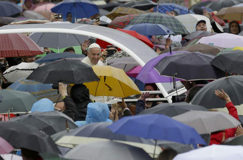 Pope Francis greets people sheltering themselves from the rain under their umbrellas as he arrives for an audience for the Holy Year of Mercy, in St. Peter's Square, at the Vatican.