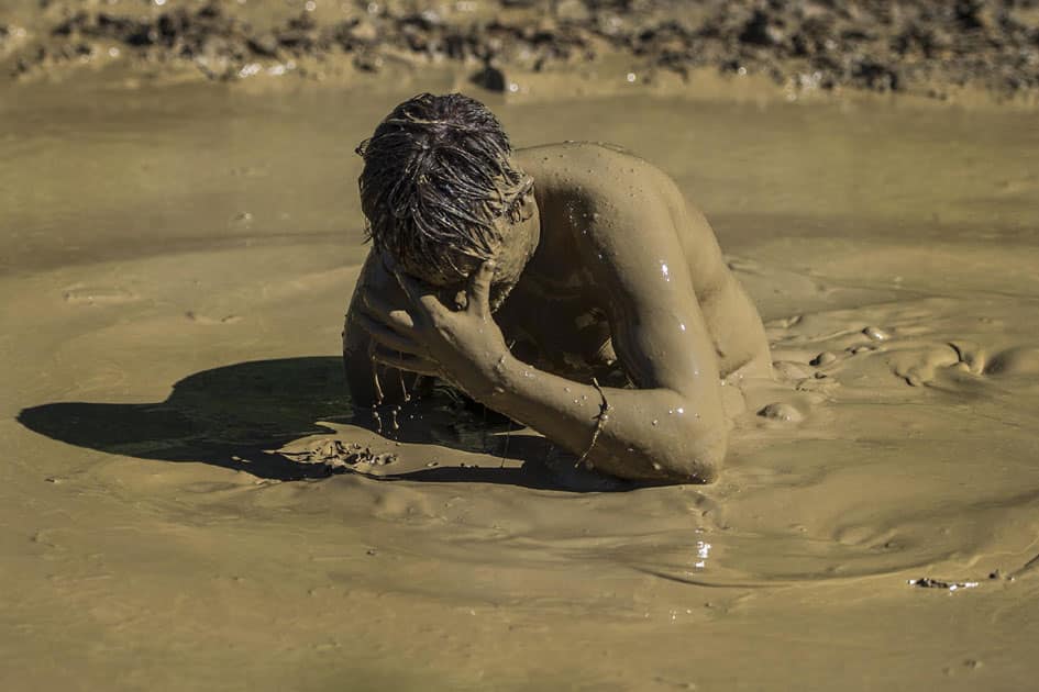 Kyle Springer wipes his eyes after swimming through a portion of a giant puddle during the Big Nasty Mud Run.
