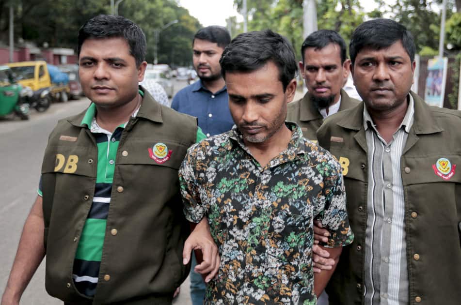 Members of Bangladesh Police Detective Branch (DB) escort a man, center, whom they have identified as Shariful Islam Shihab, a former member of the banned Islamic group Harkatul Jihad as they walk him in front of the media in Dhaka, Bangladesh.