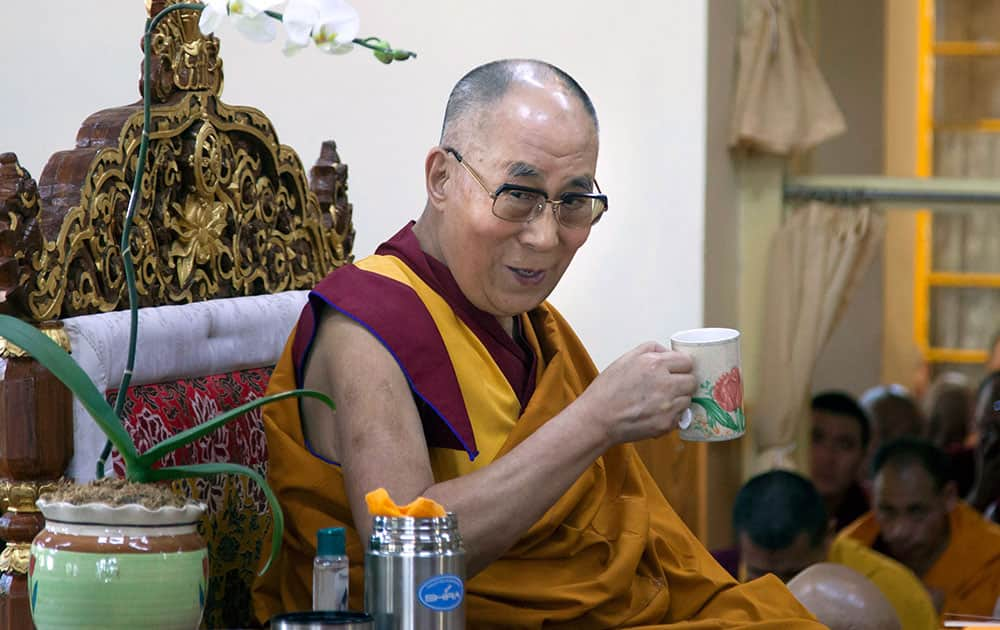 Tibetan spiritual leader the Dalai Lama smiles as he holds a cup of tea during a break in a prayer session in Dharmsala.