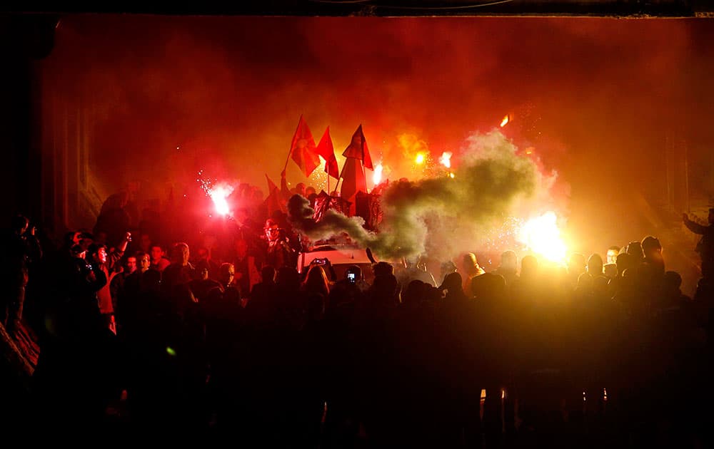 Protestors light flares and wave flags marching through a street, during an anti-government protest, in Skopje, Macedonia.