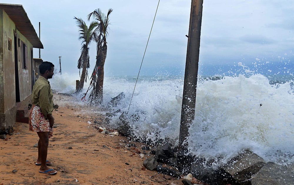 A man watches rough sea causing damage to houses in coastal areas in Thiruvananthapuram.