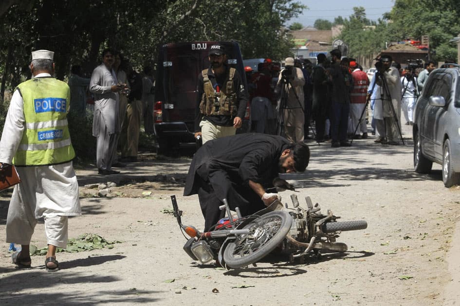 A Pakistani security official inspects a motorcycle following a bomb blast in Peshawar, Pakistan.