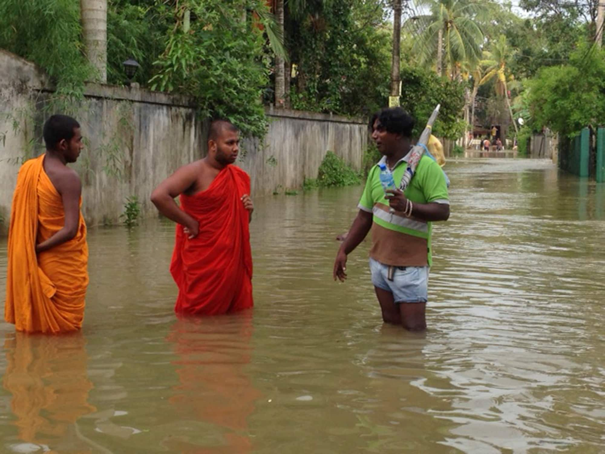 Sri Lankan Buddhist monks talk to a civilian in a street inundated with floods caused by heavy rains, in the town of Gampaha, about 29 kilometers (18 miles) north of Colombo, Sri Lanka.