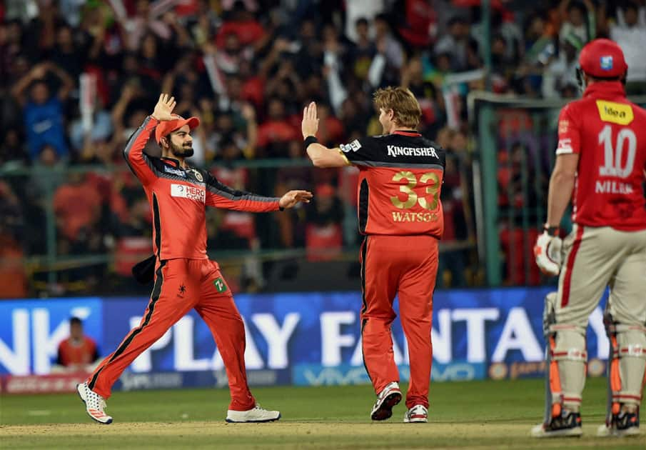 Royal Challengers Bangalores Virat Kohli (L) and Shane Watson (C) celebrate the wicket of Kings XI Punjabs David Miller during their IPL match at the Chinnaswamy Stadium in Bengaluru.