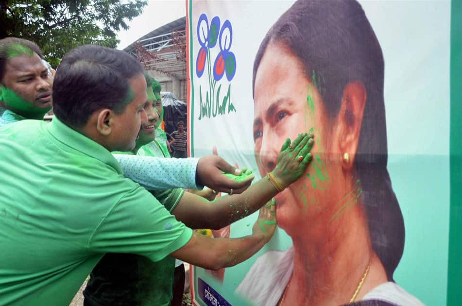 Trinamool Congress supporters smear color on a poster of party chief Mamata Banerjee as they celebrate their win in West Bengal assembly elections in Tripuras Agartala.
