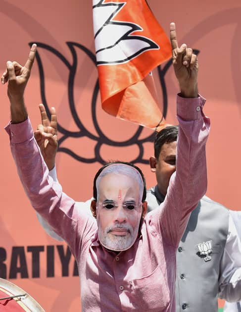 A BJP supporter, wearing mask of PM Narendra Modi, celebrates the partys performance in Assembly polls of the five states, at party headquarters in New Delhi.