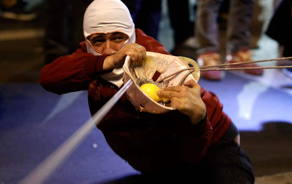 A protestor uses an improvised slingshot to throw a balloon filled with colored paint at the Parliament building, during an anti-government protest in Skopje, Macedonia.