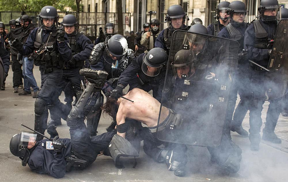 Riot police officers detain a man during a demonstration against a labor law bill in Paris.