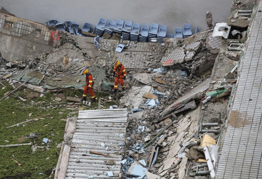 Two firefighters walk through the debris of the collapsed building at the City Universitys campus in Hong Kong.
