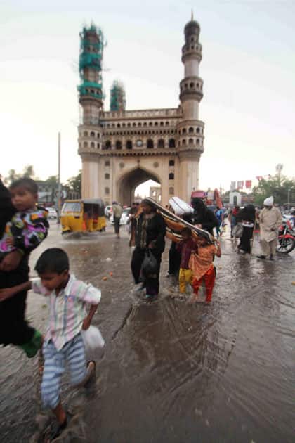 People walk on a water logged street near Hyderabads Chaar Minar after heavy rains in the city.
