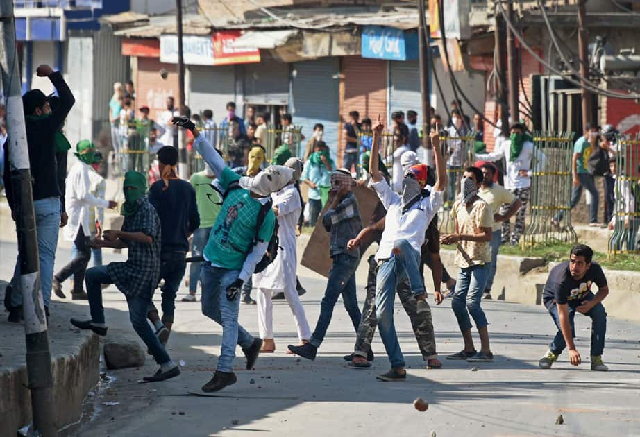 Youth throw stones amid heavy tear smoke on police during a clash in downtown area of Srinagar.
