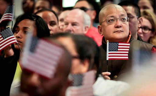 Shih Nam Sak, third from right, a Buddhist monk from Malaysia, listen as a President Barak Obama speak by taped video during a naturalization ceremony in New York.