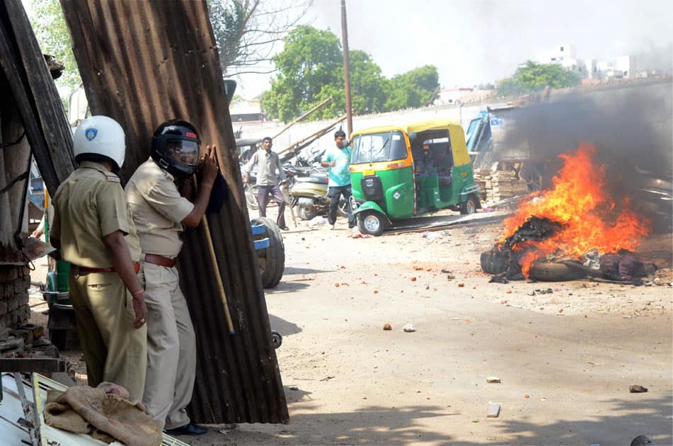 Policemen protecting themselves from stones throwing by agitated people during the during Municipal Corporation demolition drive at Bhimatalav Colony in Vadodara.