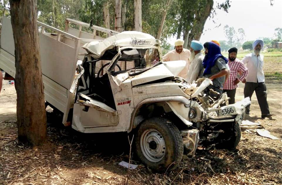 Onlookers watch a damaged vehicle which plugged into a wrongly parked tipper truck at Boparai village near Amritsar killing 10 persons.