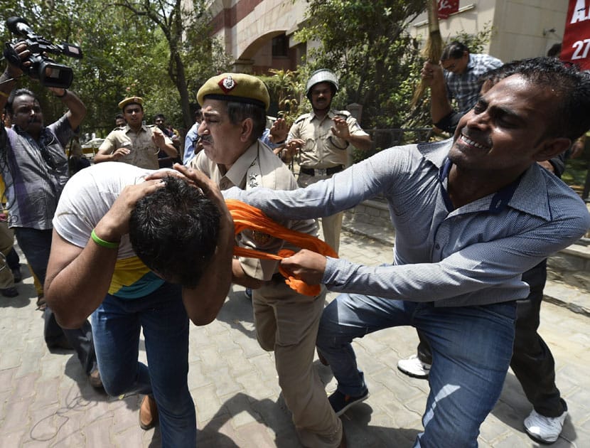 A policeman intervene as BJP and CPI workers clash during BJP protest outside the CPI(M) headquarters, damaged their signboard in protest against the murder of a party worker allegedly by Left party supporters in Kerala, in New Delhi.
