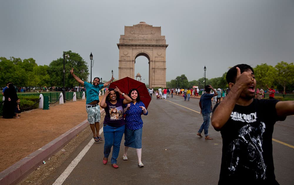 People enjoy a sudden rain and thunderstorm at the India Gate in New Delhi. After days of relentless summer heat, storm accompanied by short spells of rain brought relief to the Indian capital.