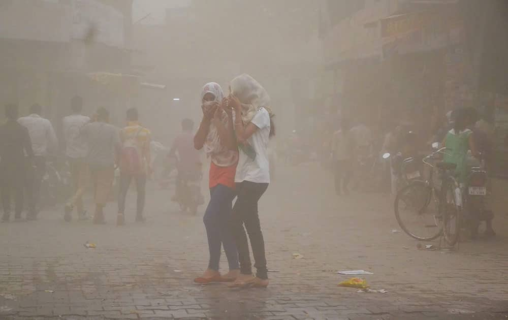 Girls cover themselves during a dust storm in Mathura.