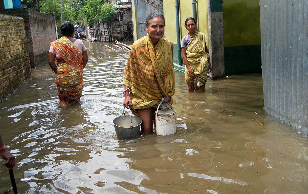 People wade through a waterlogged locality after heavy rains at Balurghat in South Dinajpur district of West Bengal.