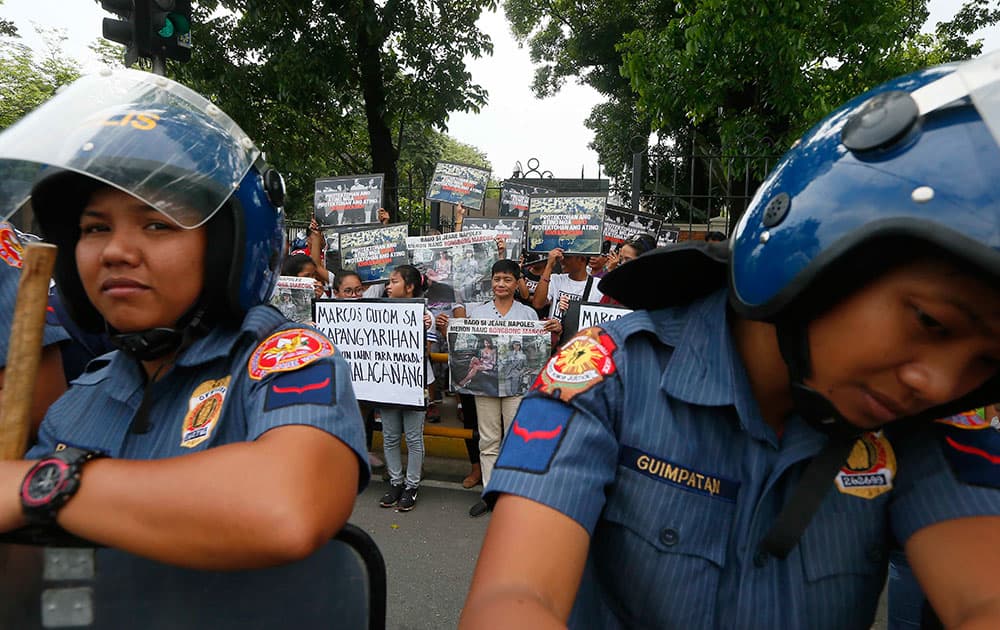 Riot police guard supporters of front-running vice-presidential candidate Rep. Leni Robredo during a protest outside the Philippine Lower House to coincide with the start of the official count of votes cast in the May 9 presidential and vice-presidential election in suburban Quezon city, northeast of Manila, Philippines. 