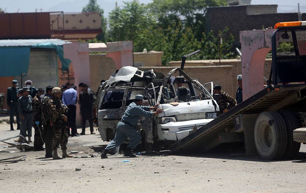 An Afghan police soldier push the destroyed vehicle on a military track at the site of a suicide attack in west of Kabul, Afghanistan.