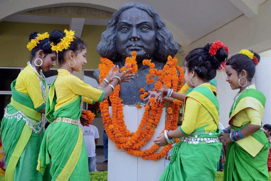 School girls in traditional attire pay tributes to the statue of Bengali poet Kazi Nazrul Islam on his 118th birth anniversary celebrations.