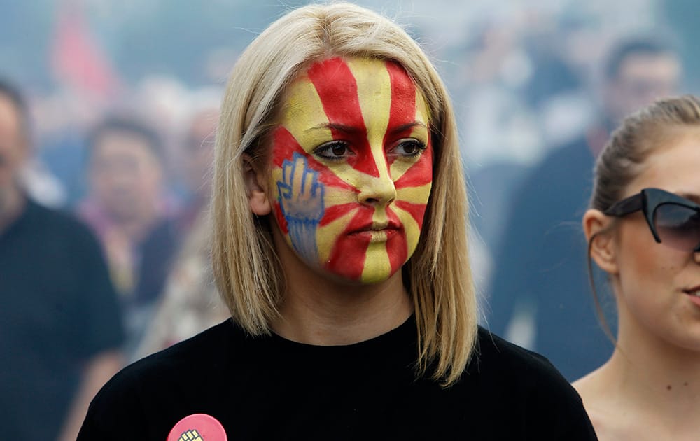 A young woman, with her face painted in the colors of Macedonian flag and a fist on her cheek, attends an anti-government protest marching through a street in Skopje, Macedonia.