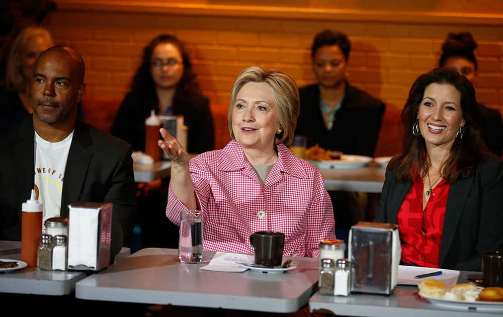 Democratic presidential candidate Hillary Clinton, center, speaks with Derreck Johnson, left, and Oakland Mayor Libby Schaaf, at the Home of Chicken and Waffles.