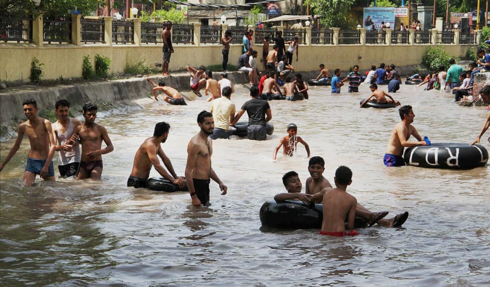 People enjoy at the Ranbir Canal to beat the heat in Jammu.