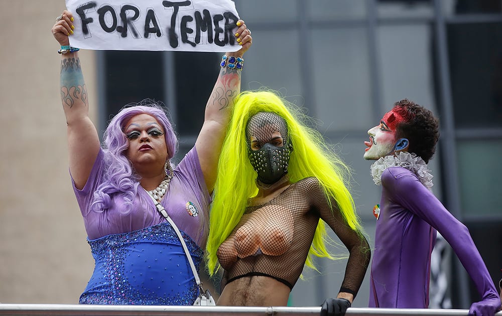 Revelers, one holding a sign that reads in Portuguese, 