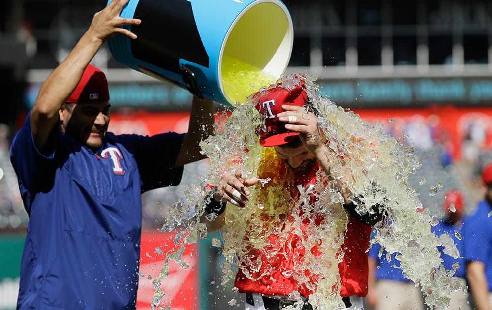 Texas Rangers starting pitcher Martin Perez, left, dumps a drink cooler on teammate Mitch Moreland to celebrate the win after a baseball game against the Pittsburgh Pirates in Arlington, Texas.