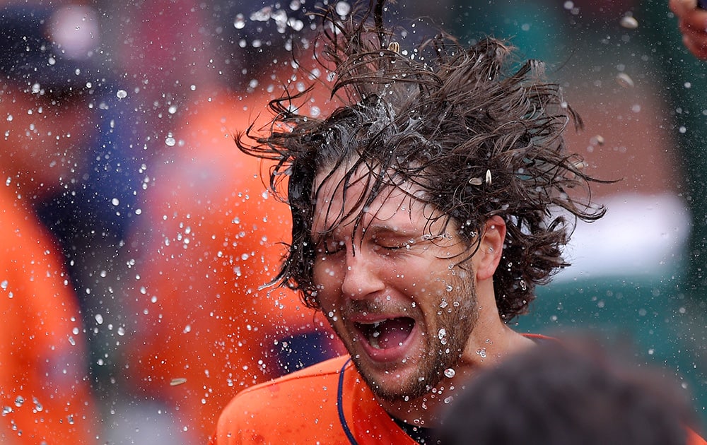 Houston Astros' Jake Marisnick has water and sunflower seed thrown at him in the dugout after hitting a two-run home run during the fifth inning of a baseball game against the Los Angeles Angels.