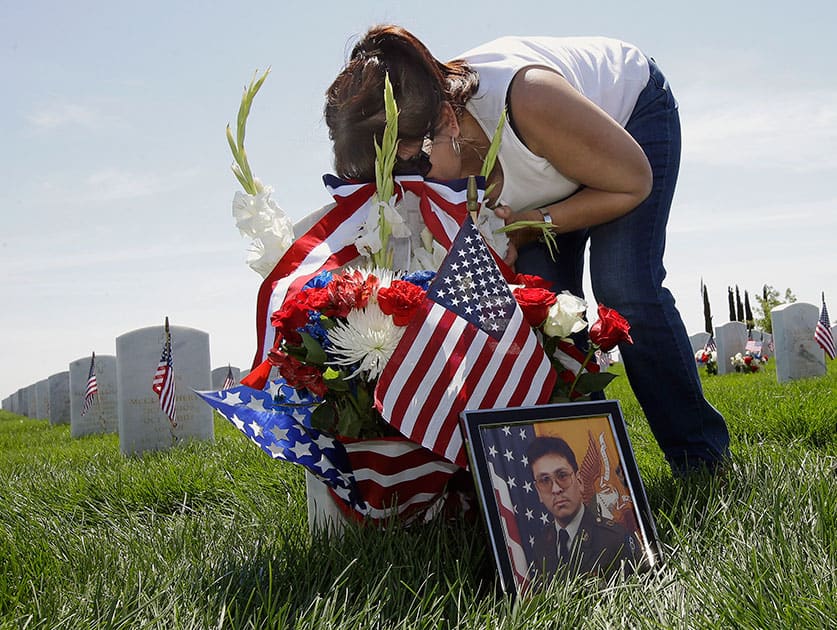 Elena Castro kisses the headstone of her brother, Army veteran Jose Rosillo, during Memorial Day at the Sacramento Valley National Cemetery, in Dixon, Calif. 