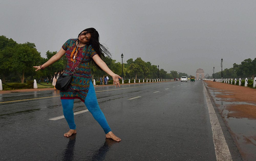 A girl dances as she enjoys the rain at Rajpath.