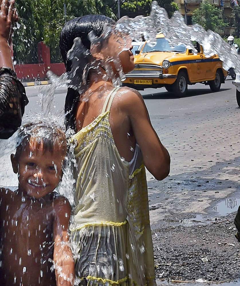 Children try to cool themselves during a heavy hot day in Kolkata.