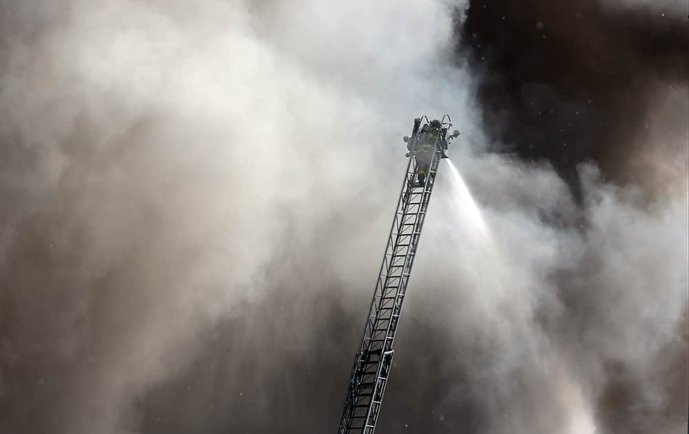 A firefighter on an aerial ladder tries to put out a fire following an explosion in a scrap pile at All Metals Recycling in Madison, Wis.