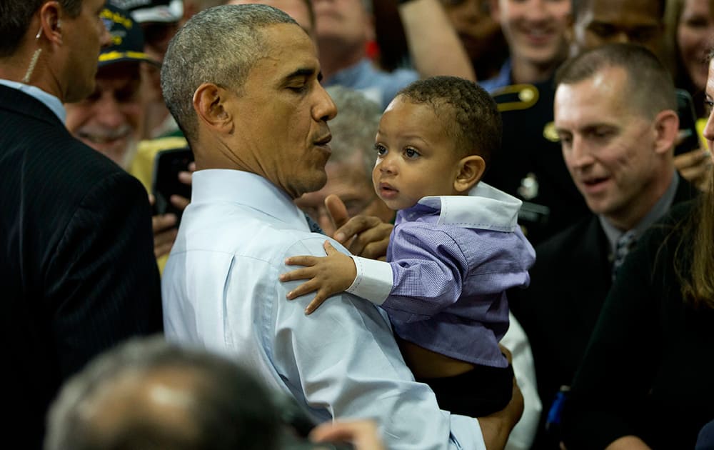 President Barack Obama carries a infant in his arms while greeting members of the audience after speaking at Concord Community High School in Elkhart, Ind. 