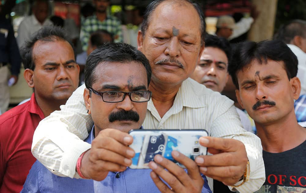 A man takes a selfie with Atul Vaidya, leader of Hindu hardliner organization Vishwa Hindu Parishad, foreground, outside a court, in Ahmadabad.