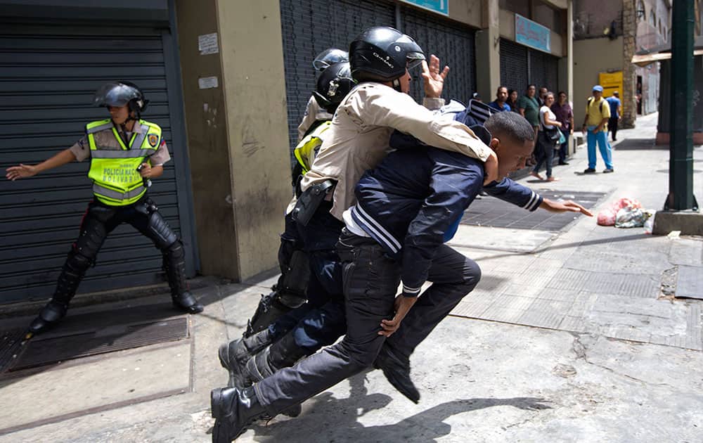 A National Bolivarian Police officer rescues a man who was being attacked by protesters, who then threw rocks at them, during a protest demanding food a few blocks from Miraflores presidential palace in Caracas, Venezuela.