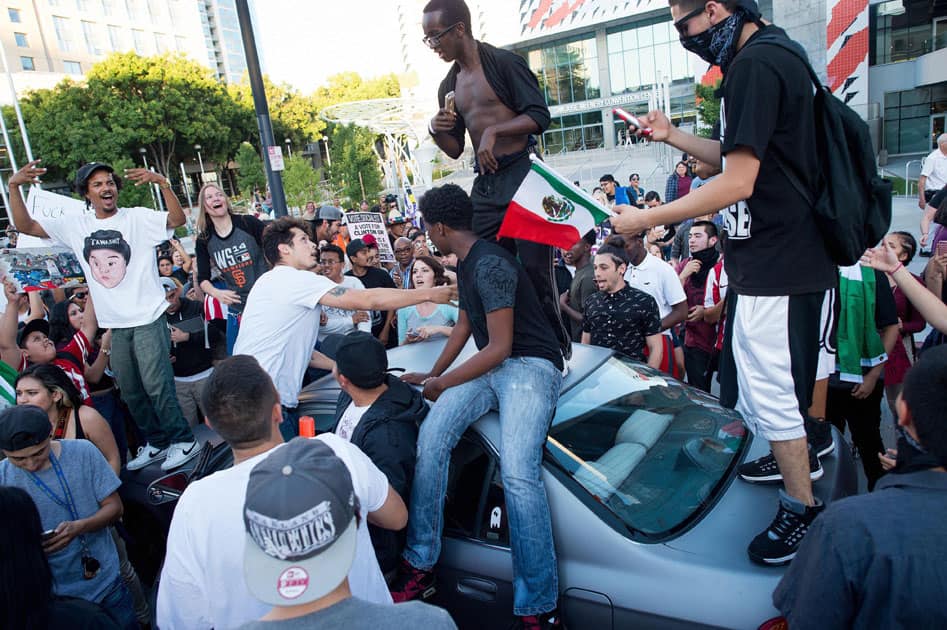 Protesters against Republican presidential candidate Donald Trump climb on a car outside a Trump campaign rally in San Jose, Calif.