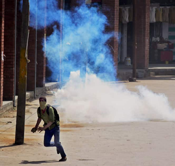 A youth throws a stone on the police amid tear gas during a clash at Nowhatta in Srinagar.
