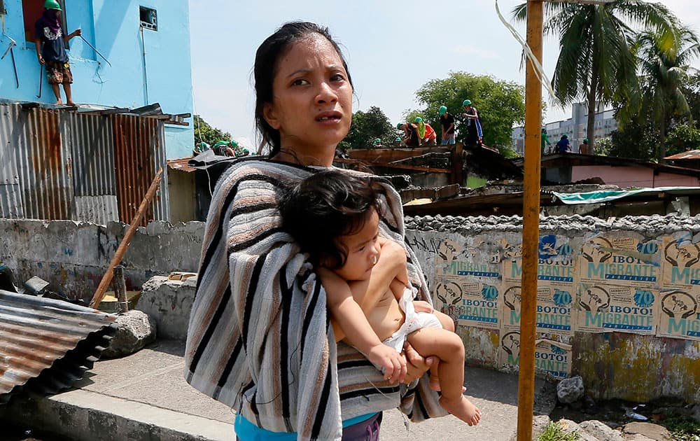 A mother carries her child as she walks away from her shanty home as demolition teams remove her makeshift community at suburban Quezon city northeast of Manila, Philippines.